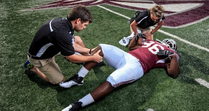 Athletic trainers treating a football player on the field